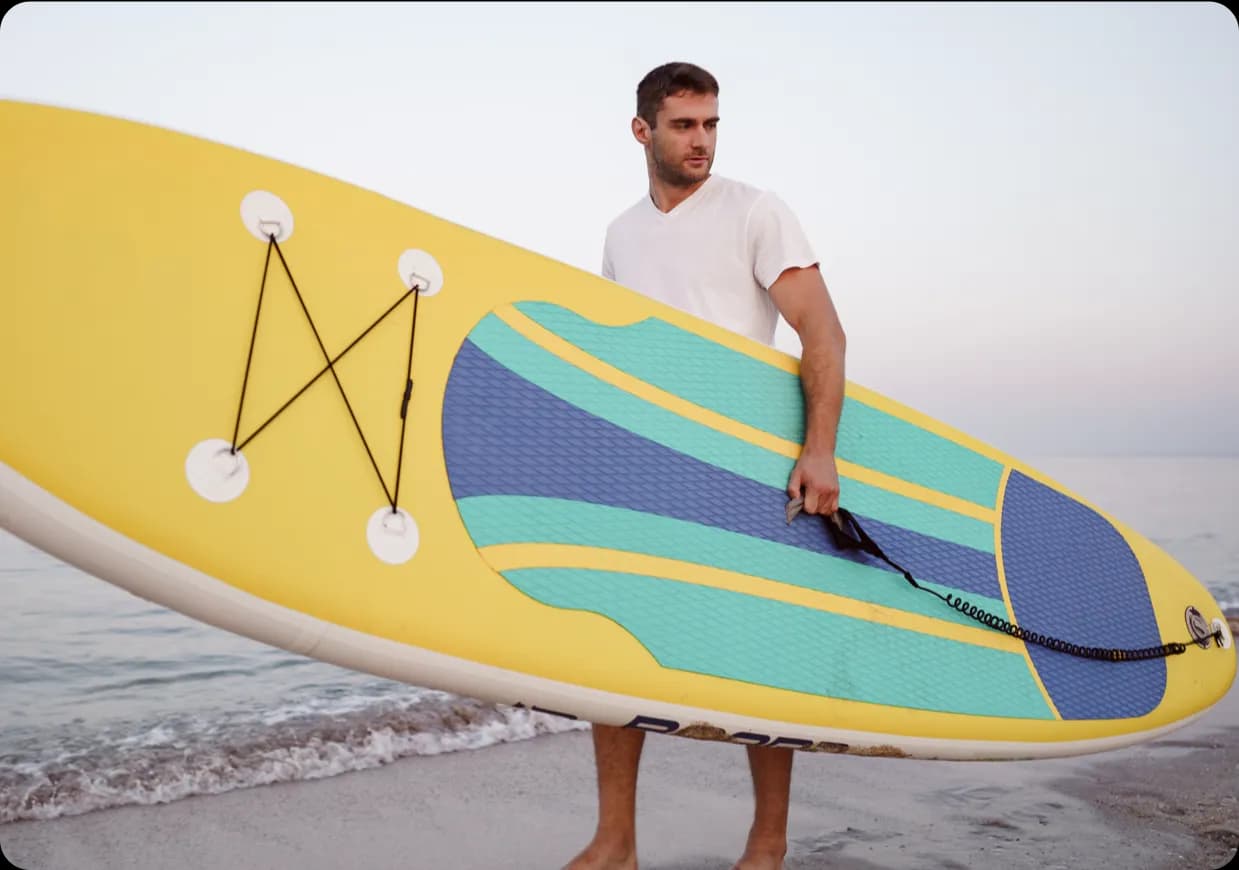 A man holding a yallow paddle board.