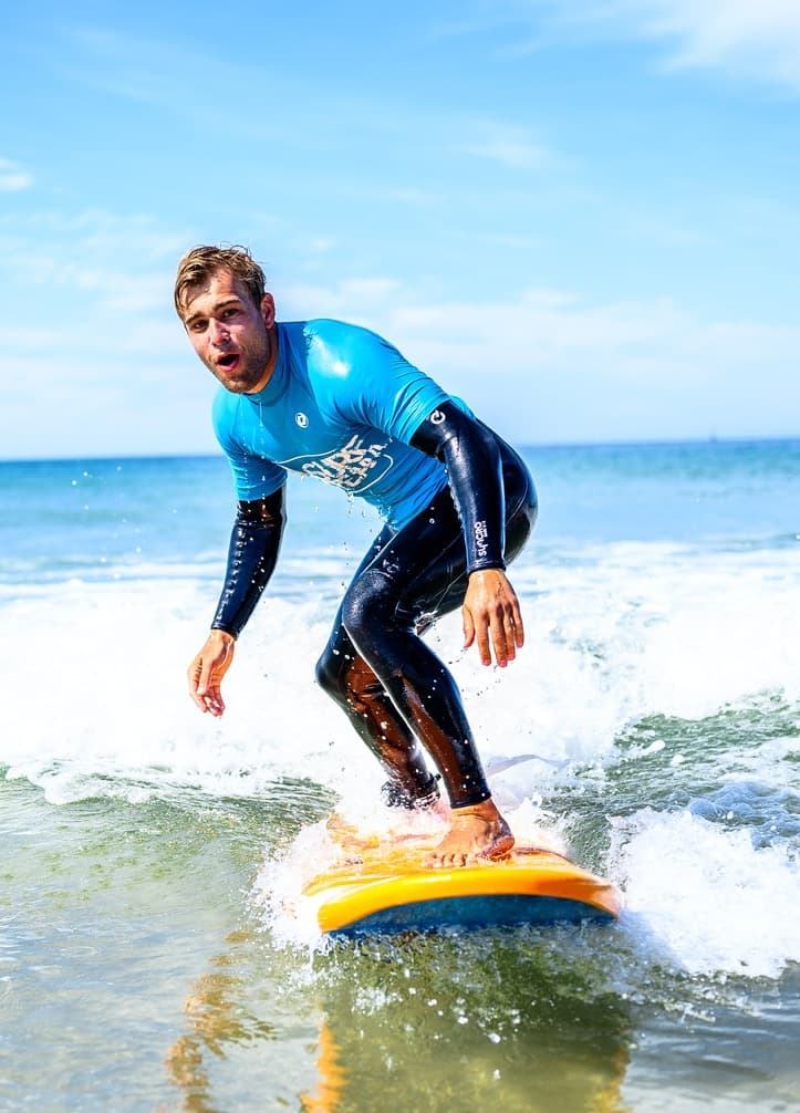 Young surfer riding a wave during a surf lesson at the beach.