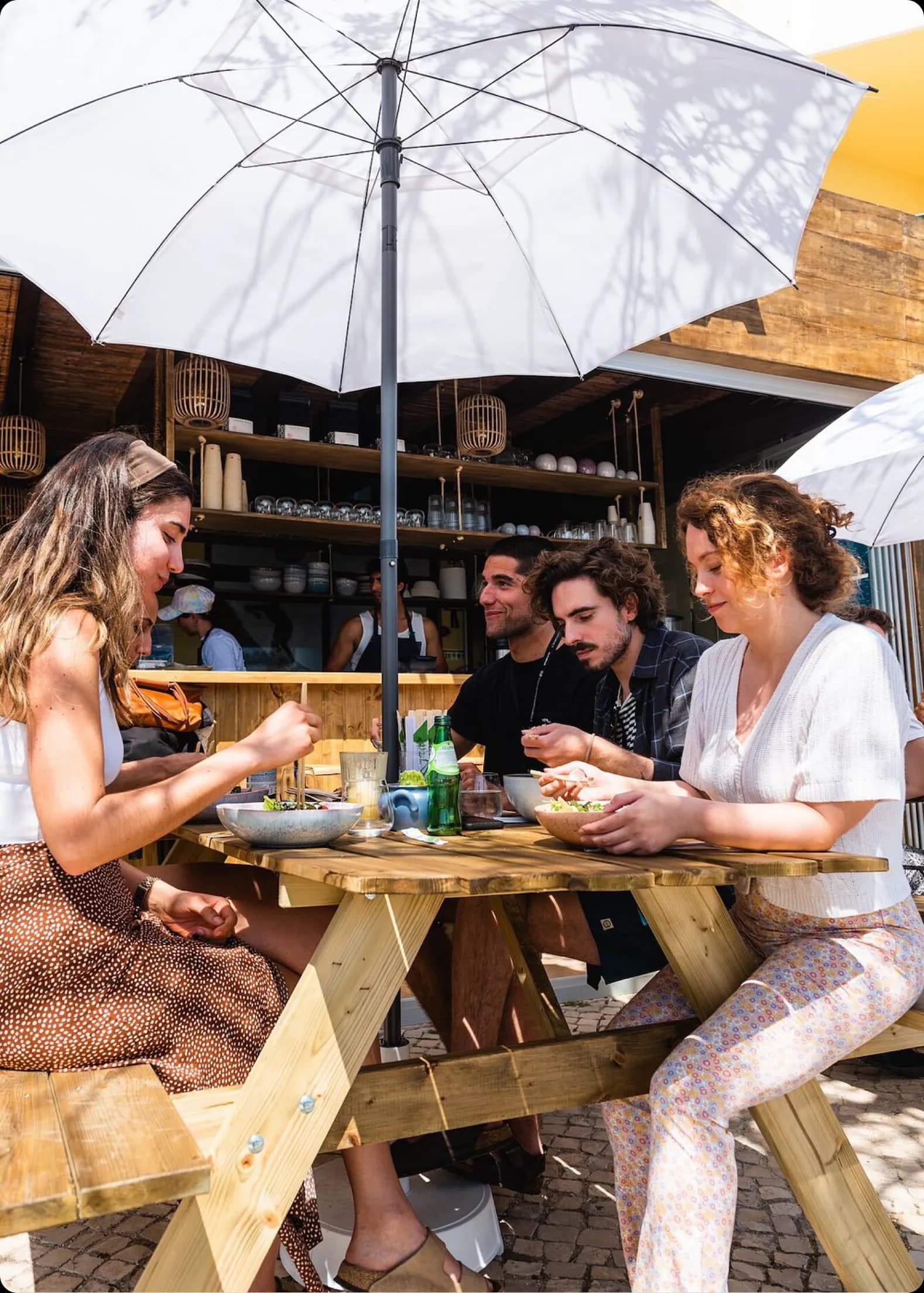 A group of friends sharing a meal and enjoying good company at a sunny outdoor table, embodying the spirit of community.
