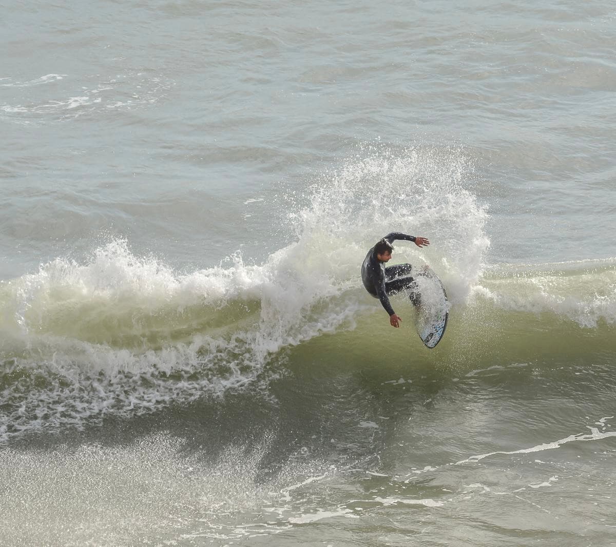 Surf instructor guiding a smiling student on a surfboard in the ocean.