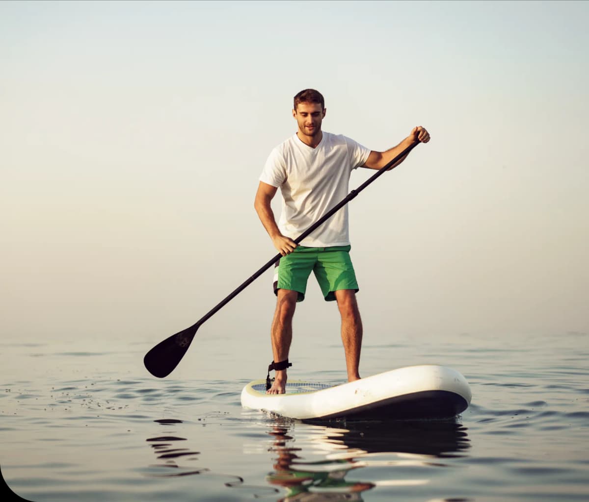 Young man in t-shirt and shorts floating on a SUP board